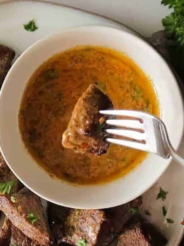 a steak bite being dipped in a bowl of cowboy butter sauce
