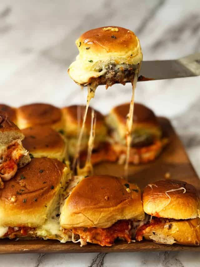 a meatball slider being picked up off a cutting board of sliders