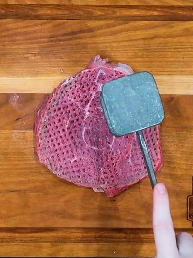pounding the steak flat with a meat tenderizer