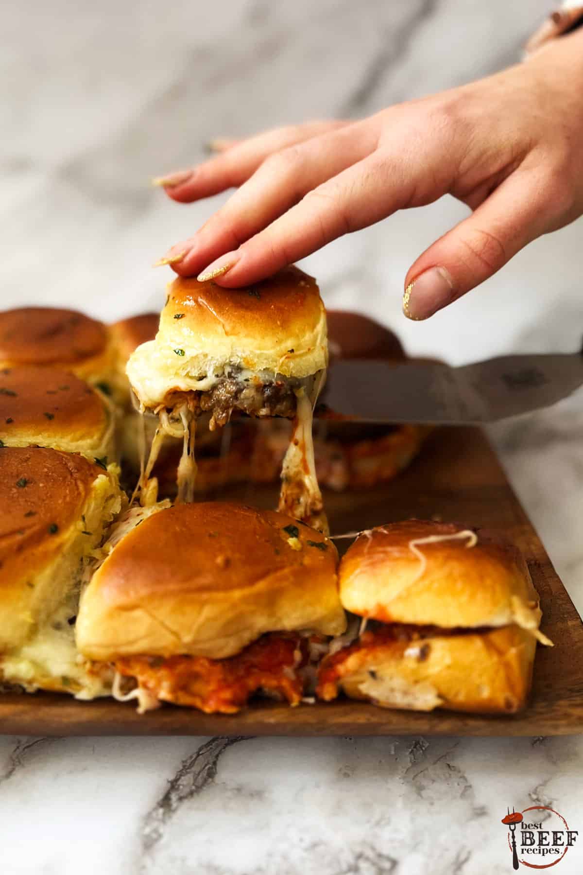 a meatball slider being separated from the rest by a hand