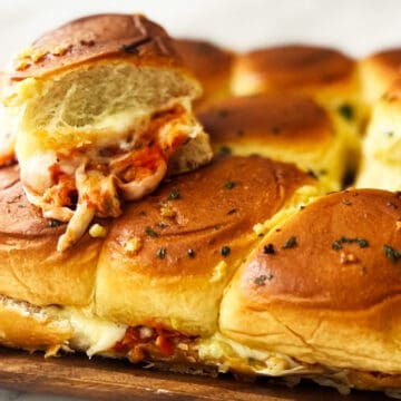 a stack of meatball sliders showing off cheese pulls and sauce