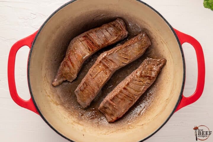 the steak chunks browning in a pot