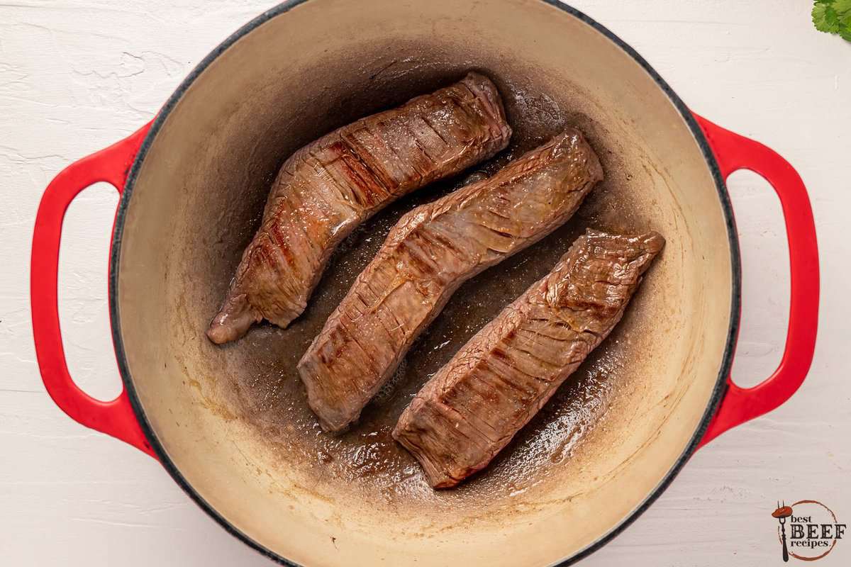 the steak chunks browning in a pot