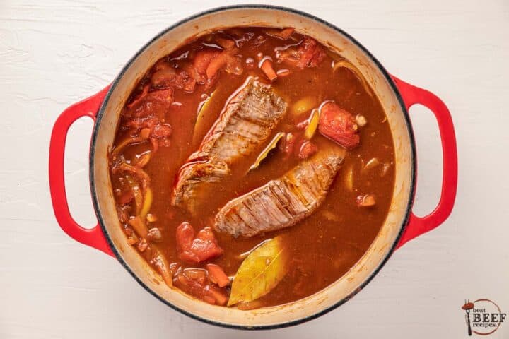 ropa vieja stewing in a pot before the beef has been shredded