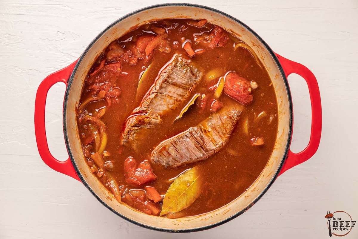 ropa vieja stewing in a pot before the beef has been shredded