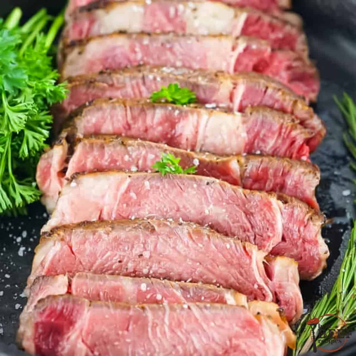 sliced steak on a pan with herbs