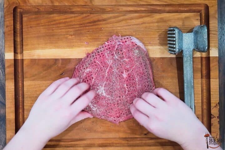 tenderized steak with added seasonings on a cutting board