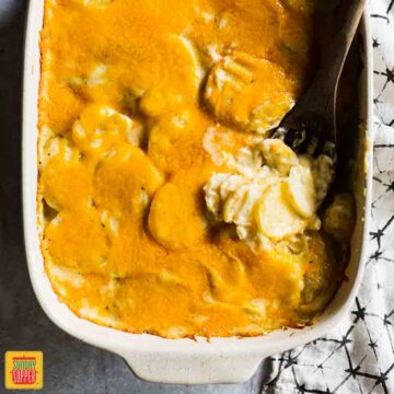 easy scalloped potatoes in a white dish with a serving spoon