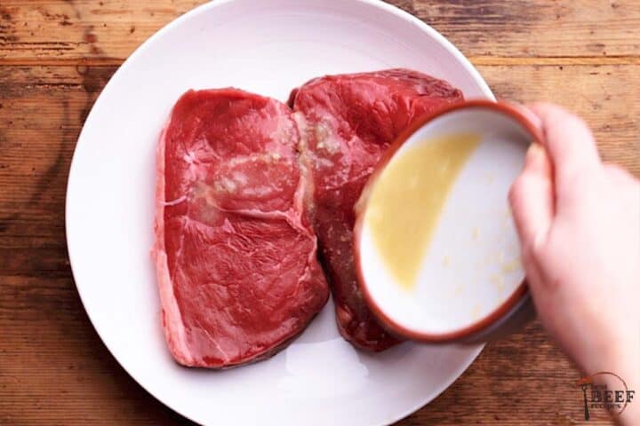 pouring marinade for sirloin steak over sirloin steak on a plate