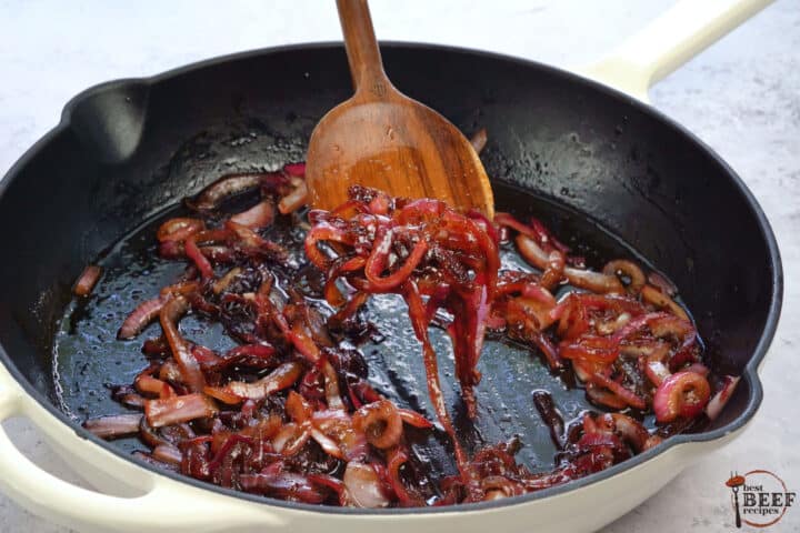caramelized onions in a skillet with a wooden spoon