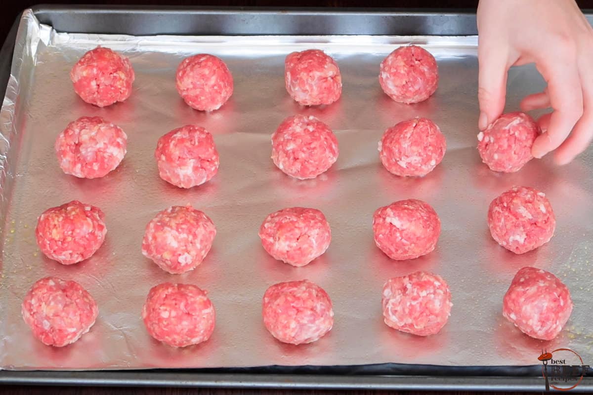 raw meatballs rolled into balls and placed on a baking sheet