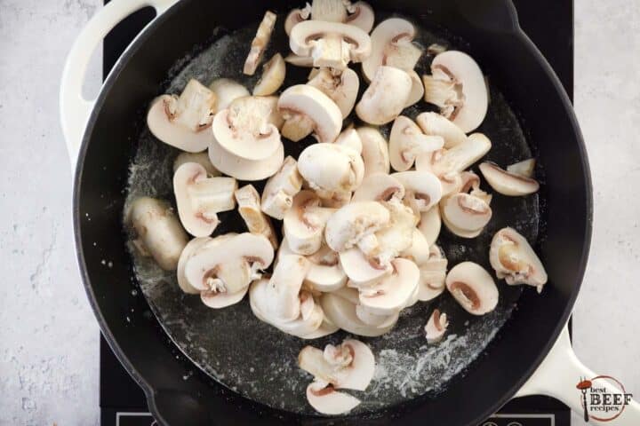 adding mushrooms to a skillet with melted butter