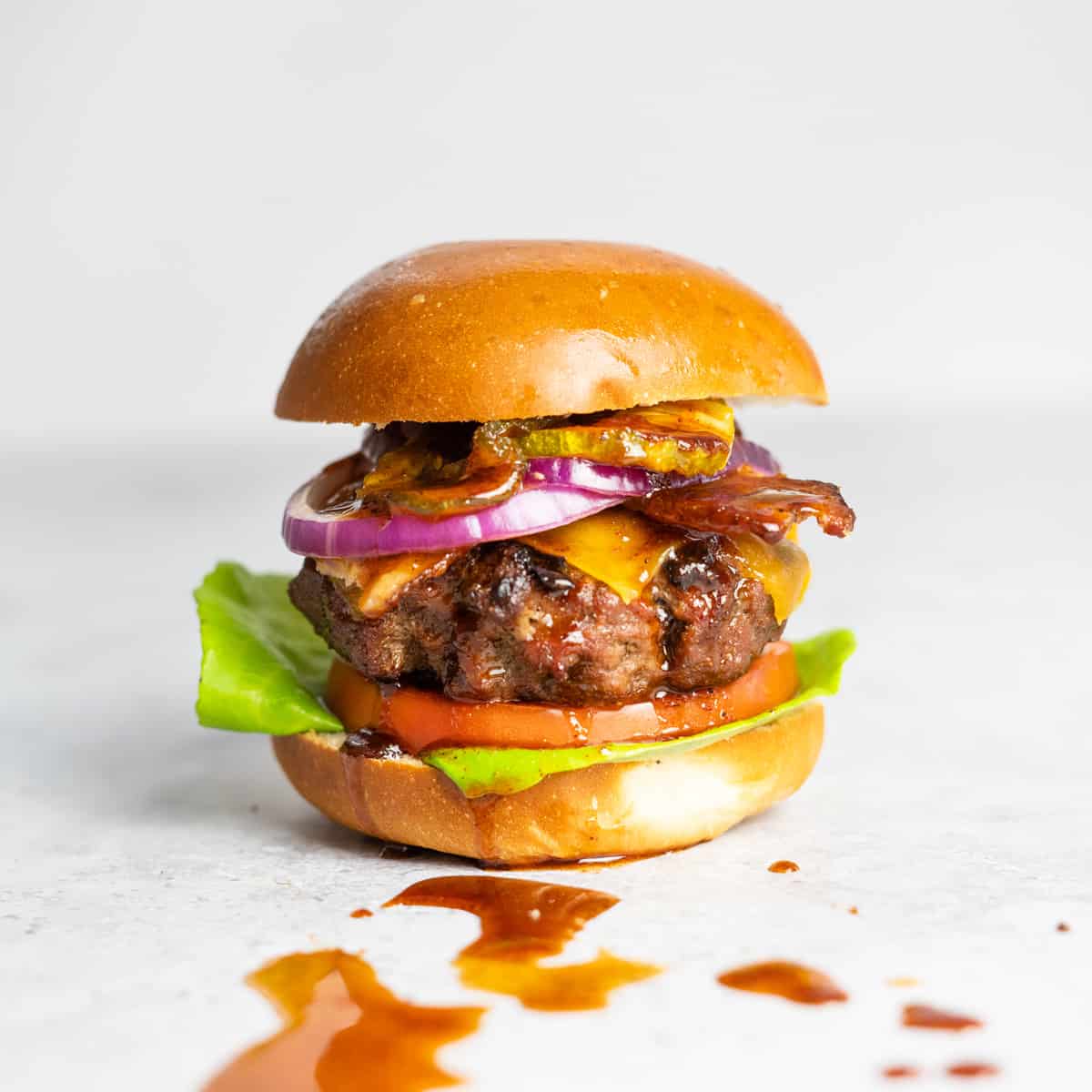 bbq burger with dripping bbq sauce on a white surface