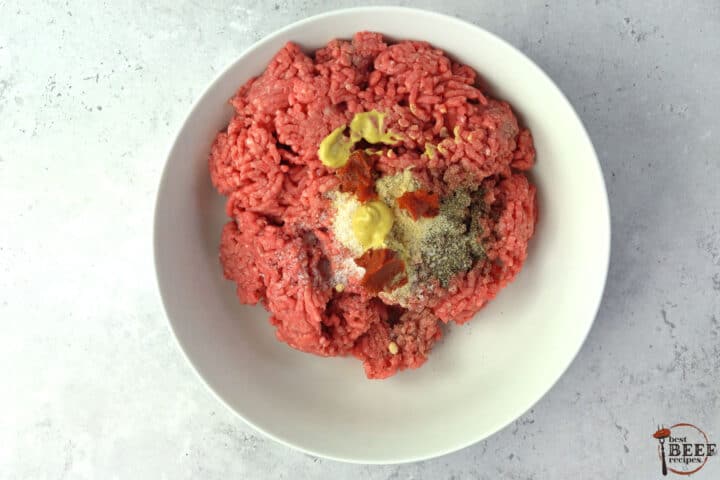 ground beef with seasonings in a white bowl unmixed