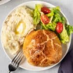 a dinner plate of beef wellington, salad, and mashed potatoes with butter