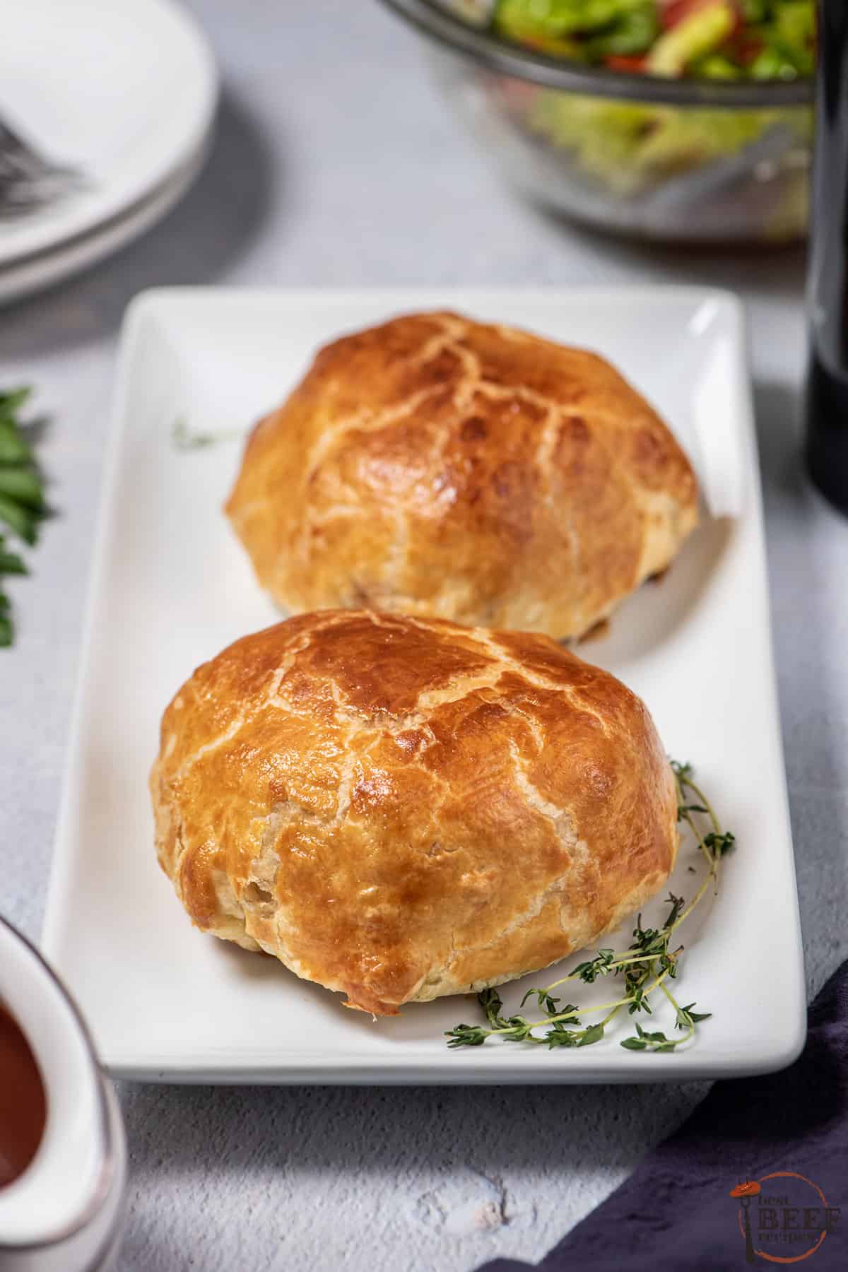 two beef wellingtons on a serving dish with extra thyme