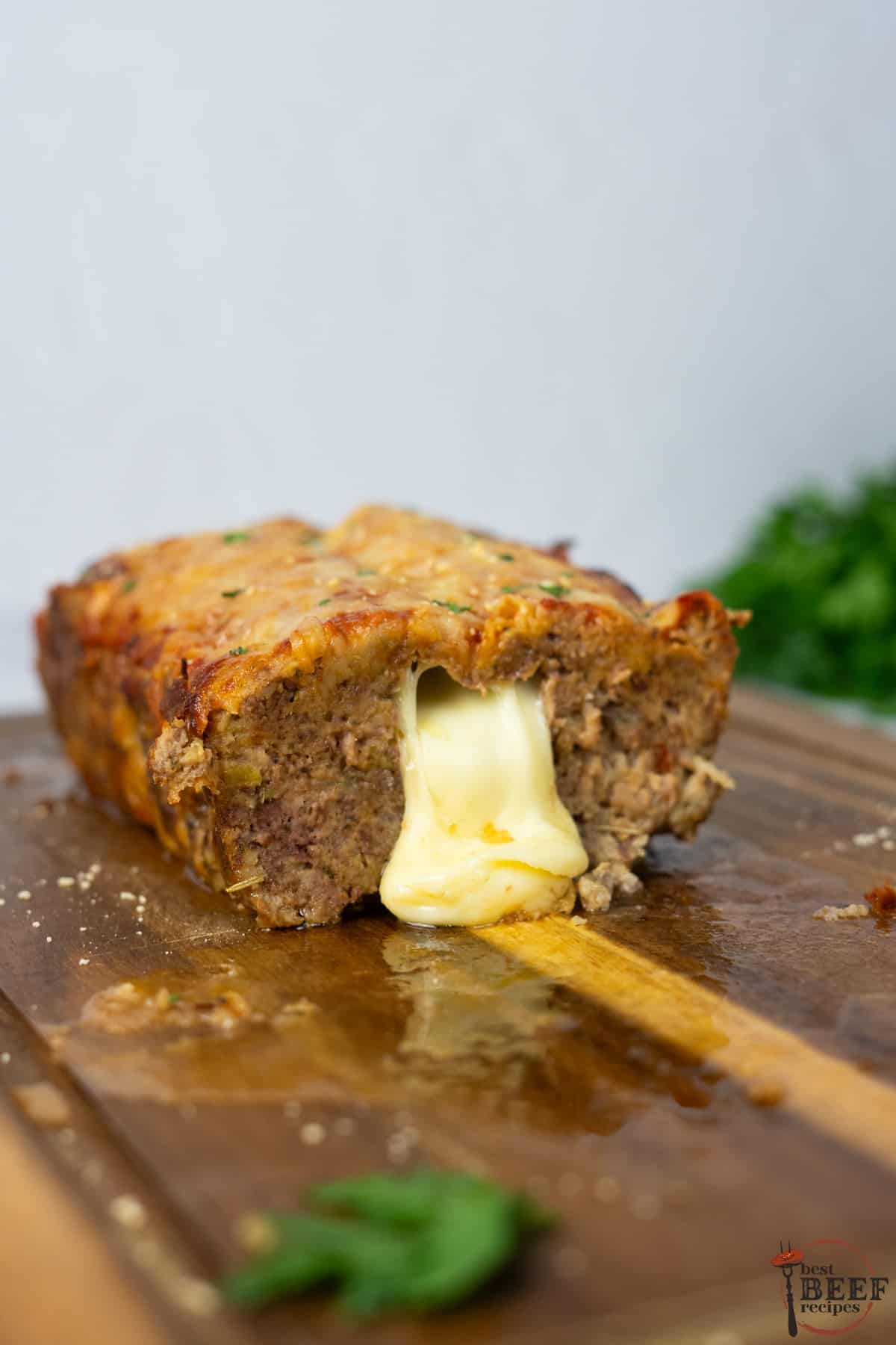 Italian meatloaf cut in half with cheese pouring out of the middle