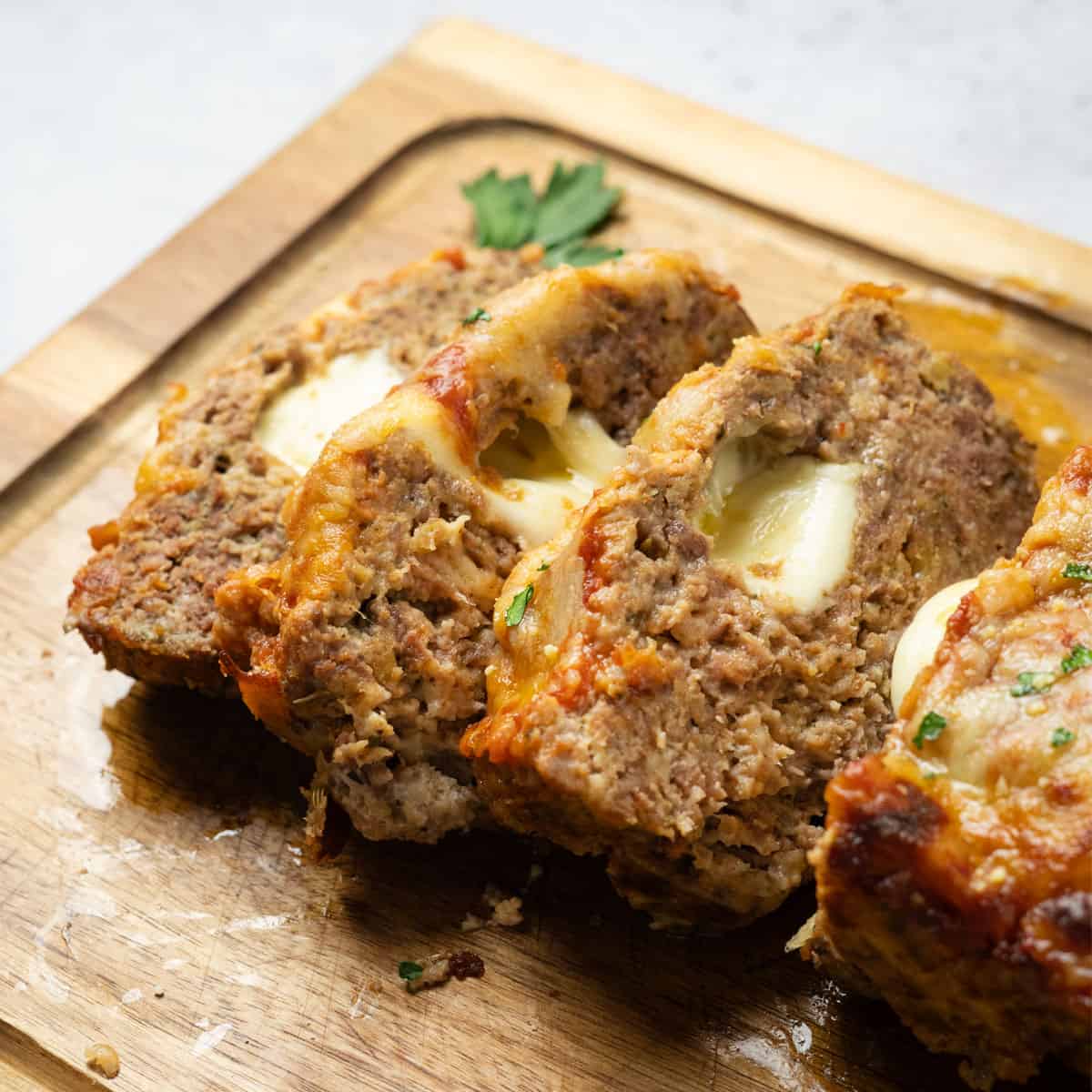 close up of Italian meatloaf sliced on a wood cutting board