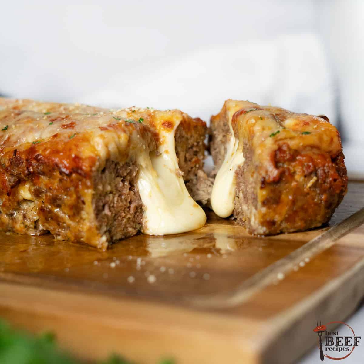 close up of Italian Meatloaf cut in half with cheese pouring out from the center