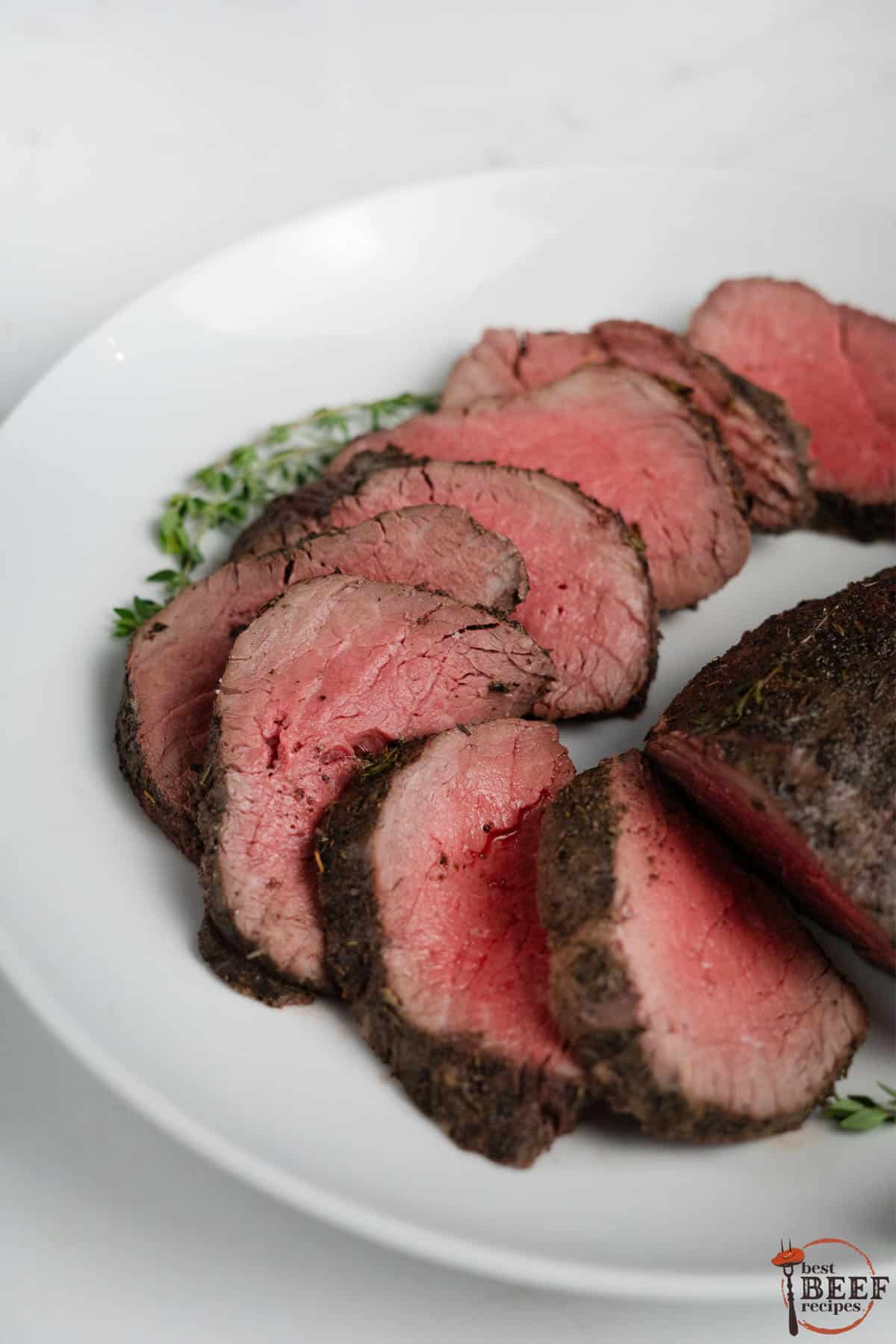 close up of sliced beef tenderloin on a white plate