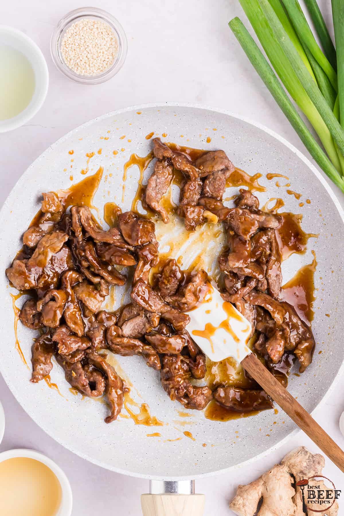 mongolian beef mixed with sauce in a pan
