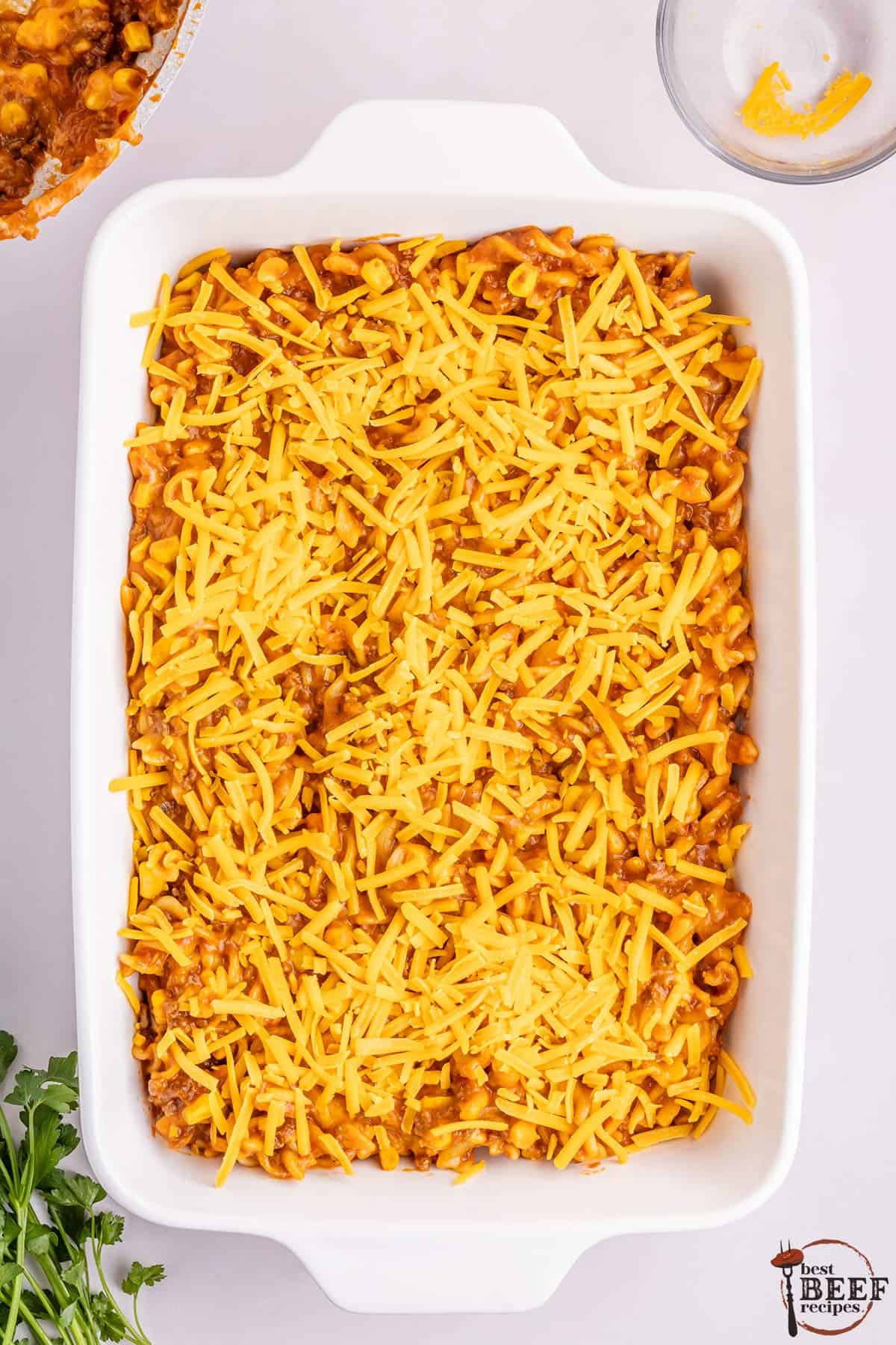 the mixed casserole poured in a dish and topped with cheddar cheese