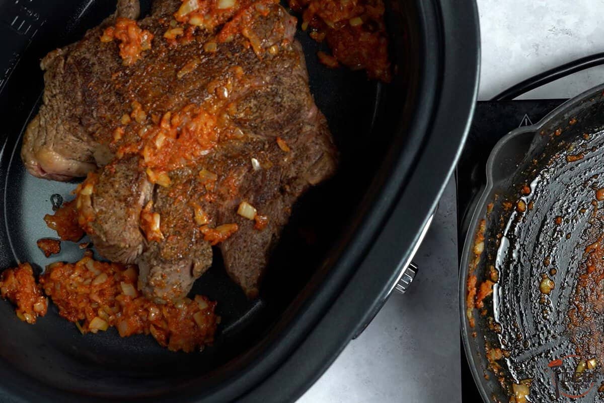 seared roast beef in slow cooker with tomato and onion mixture
