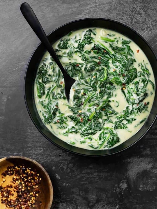 a black serving bowl of steakhouse creamed spinach with extra pepper flakes