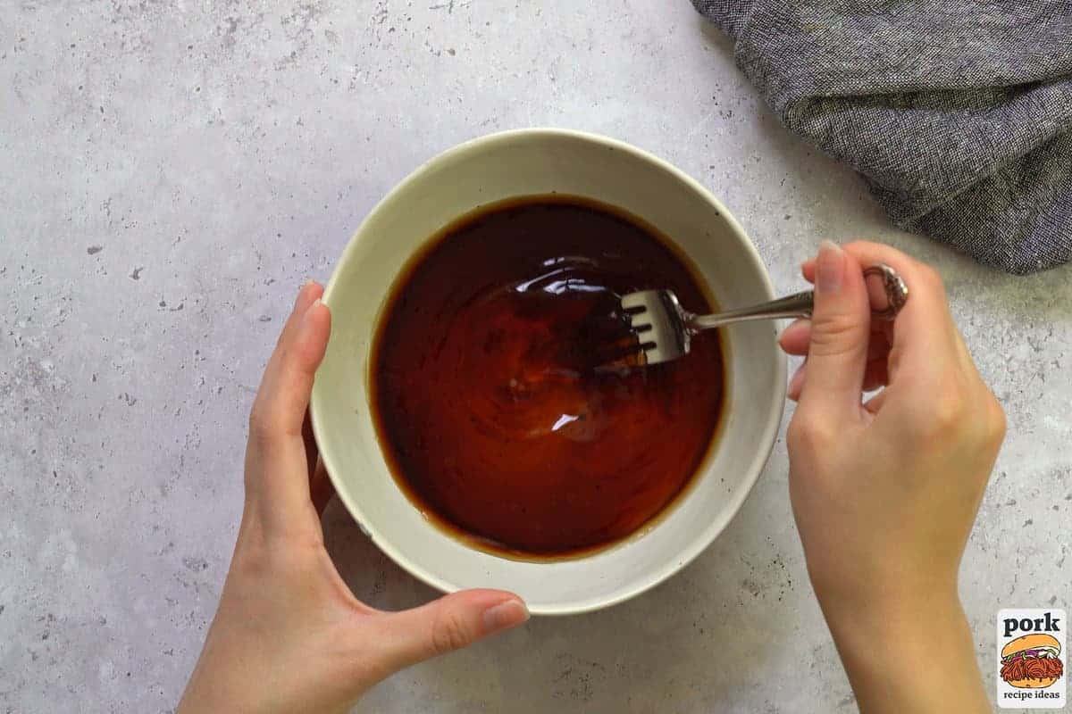 stirring honey garlic sauce for pork tenderloin in a bowl