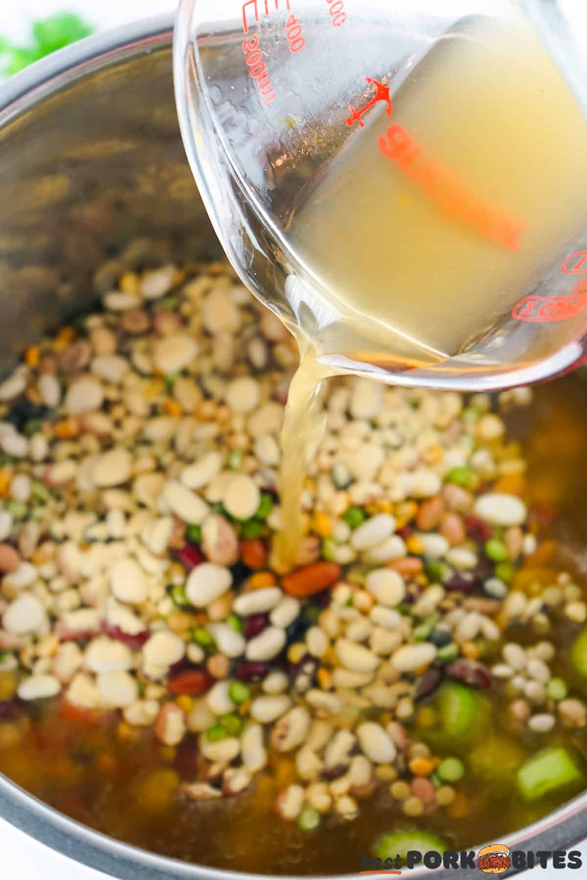 broth being poured into a pot of beans and vegetables