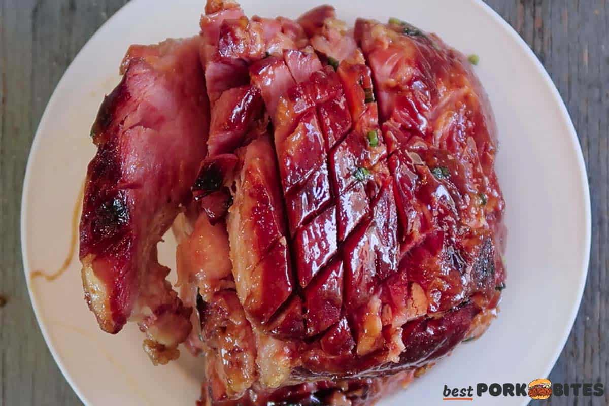 top view of cooked ham on a plate, partially sliced