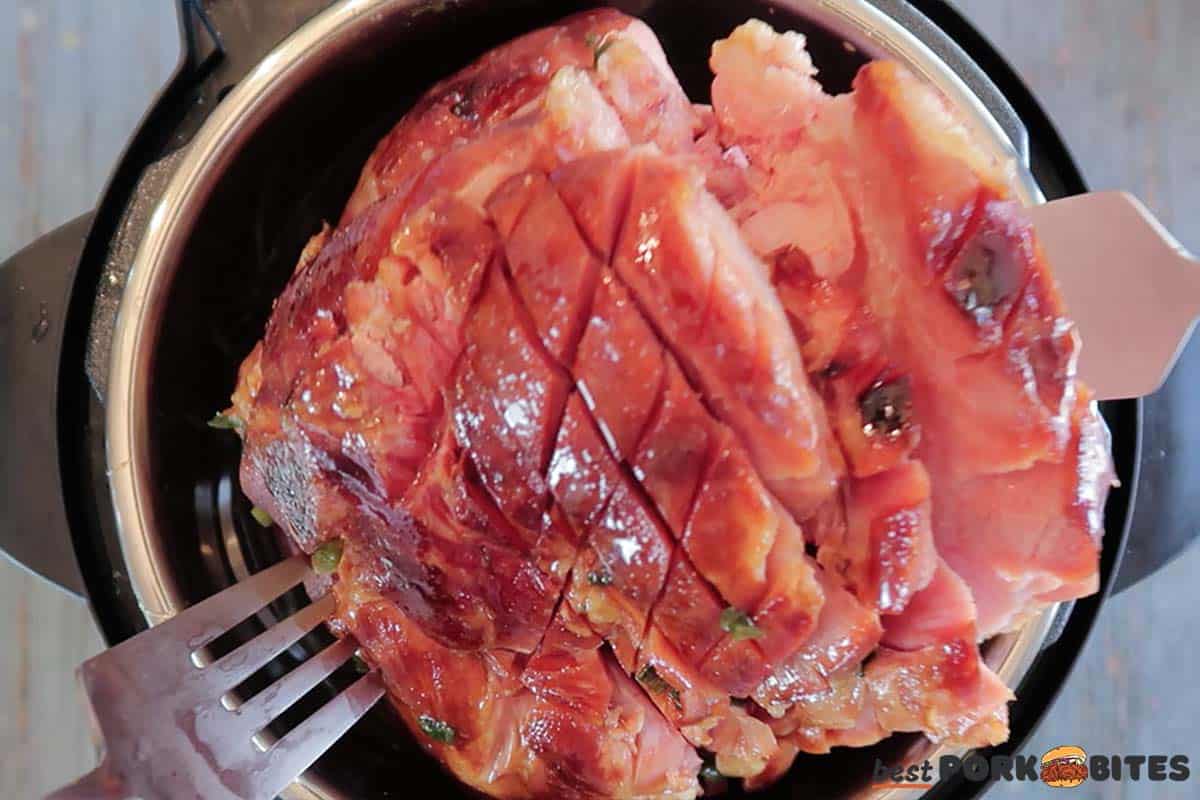 cooked ham being lifted out of the instant pot with two forks