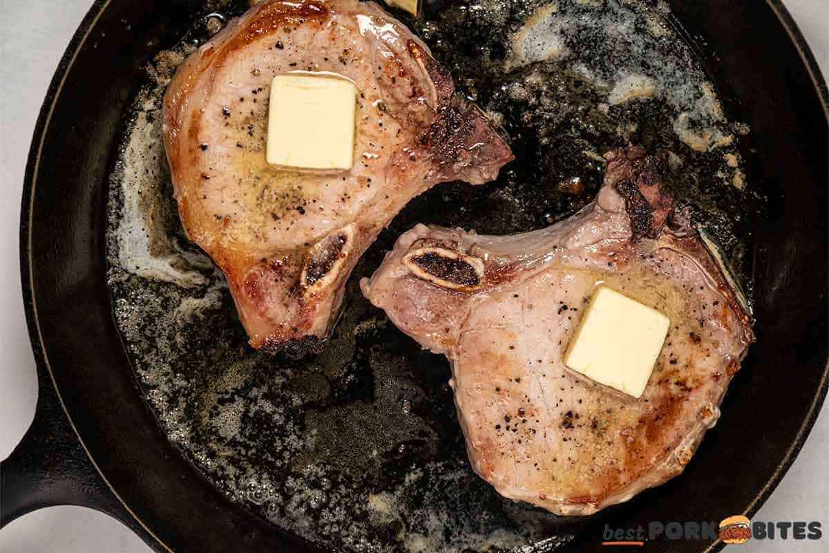 pork chops basted in butter in a black skillet