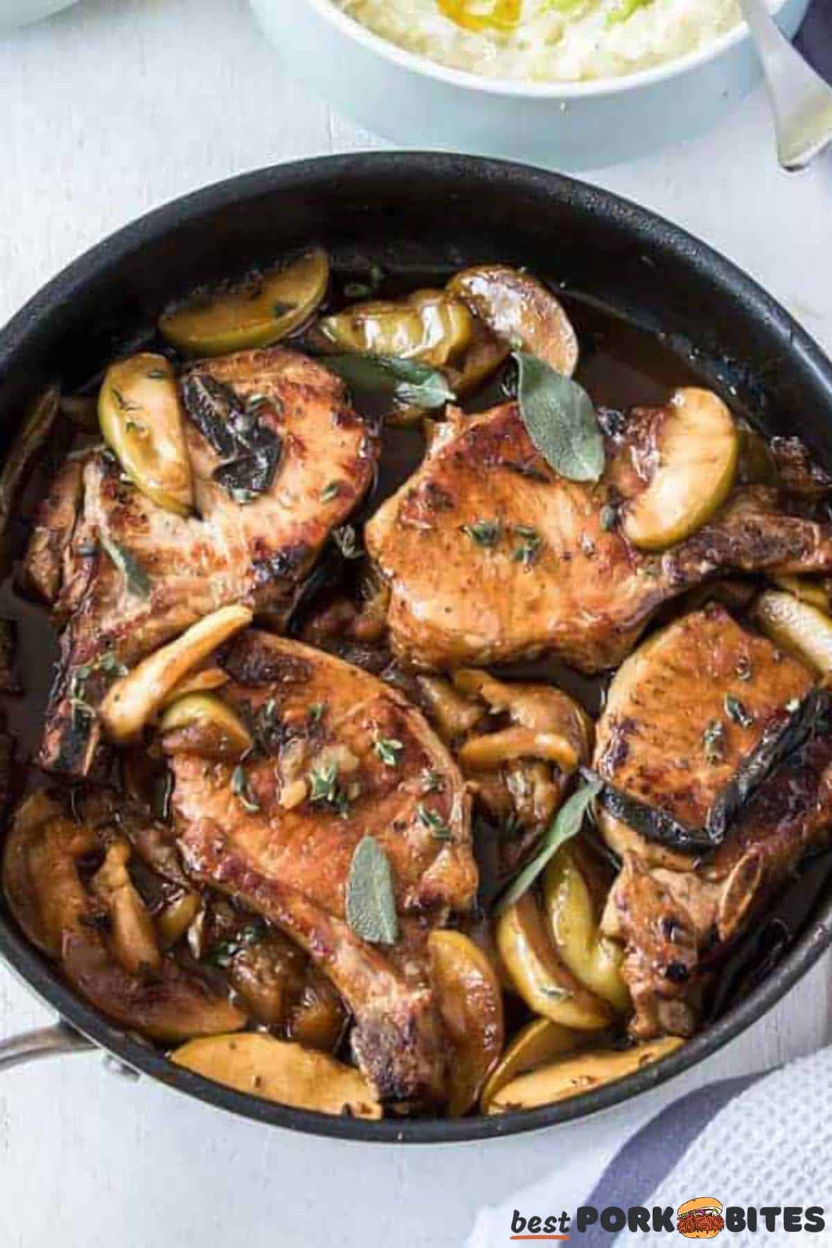 pork chops in black pan with apples and herbs