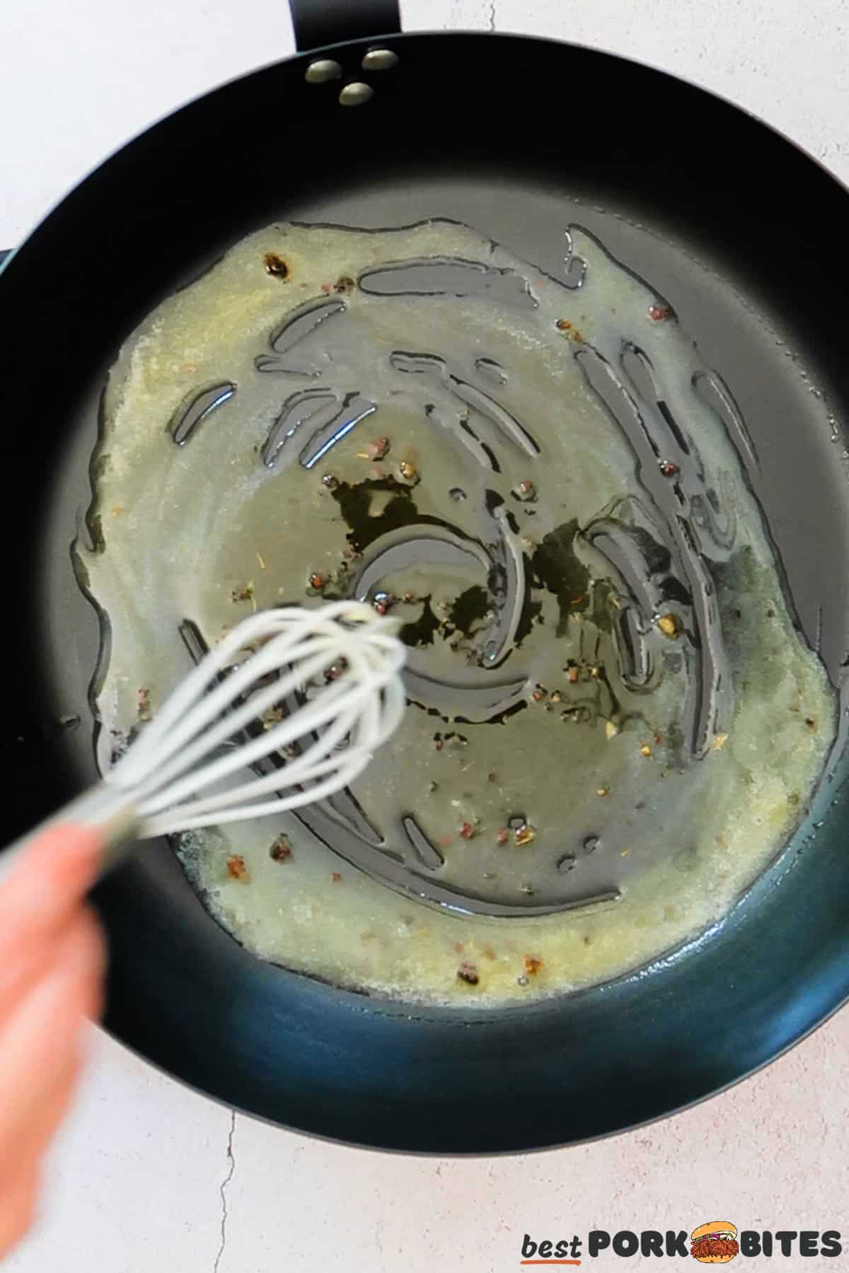 a pan with melted butter and pork drippings being whisked