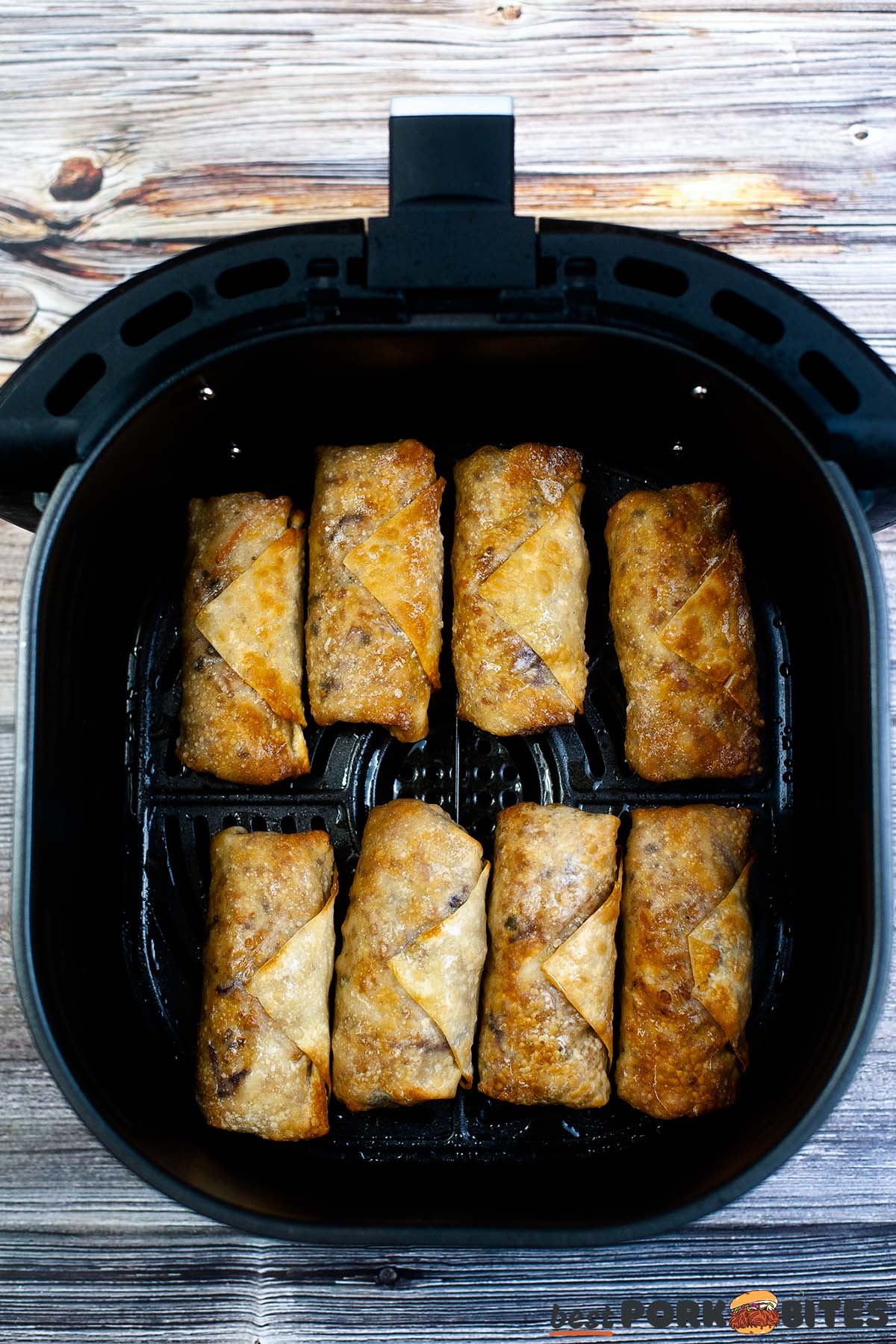 eight cooked egg rolls in an air fryer