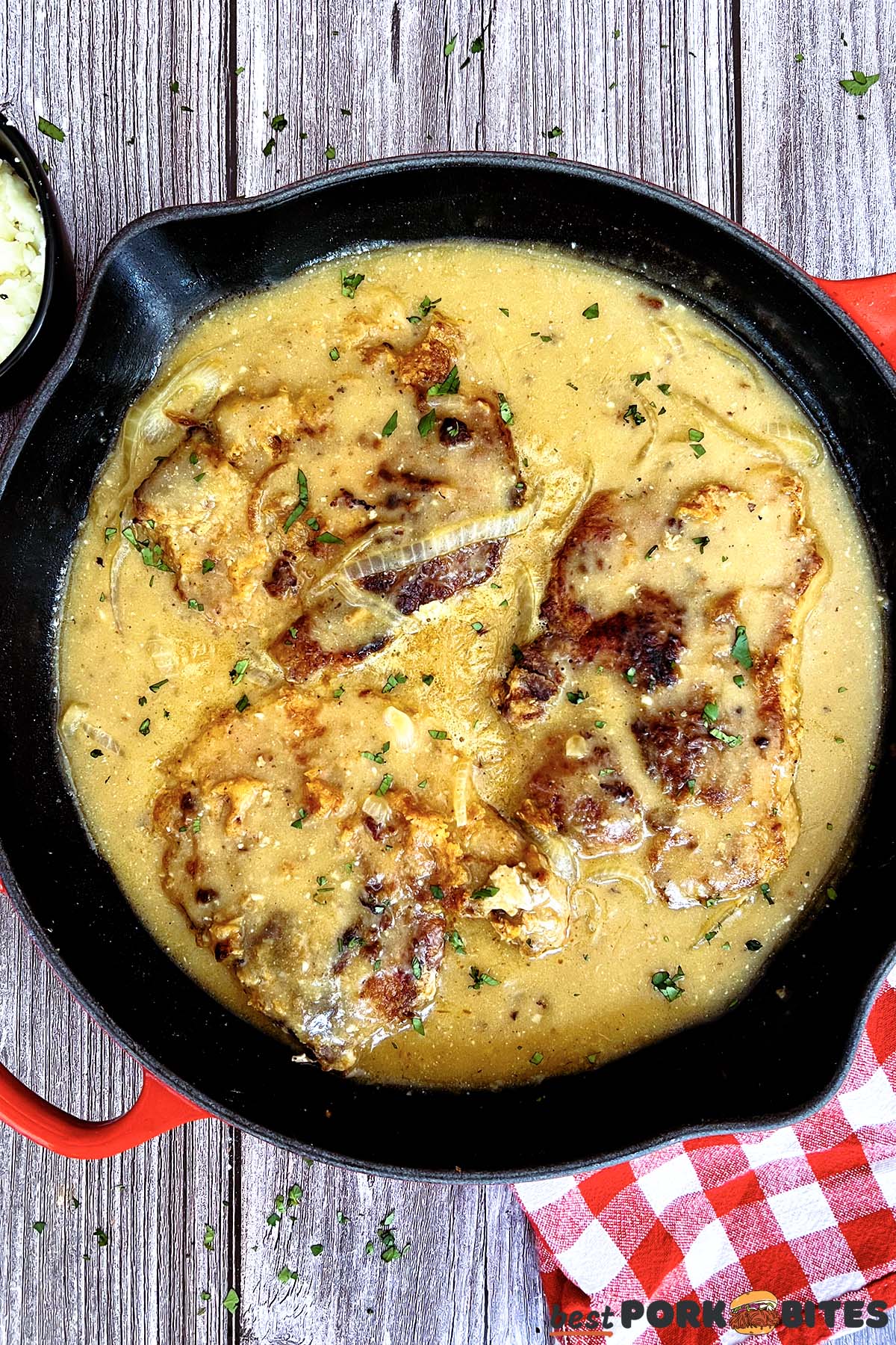 pork chops in a pan with onion gravy