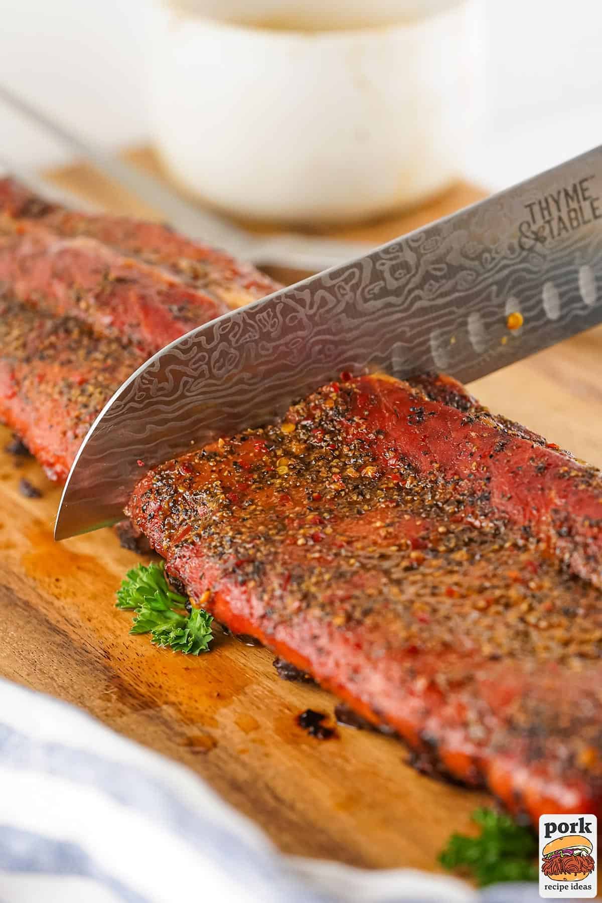 smoked bbq ribs being sliced with a knife