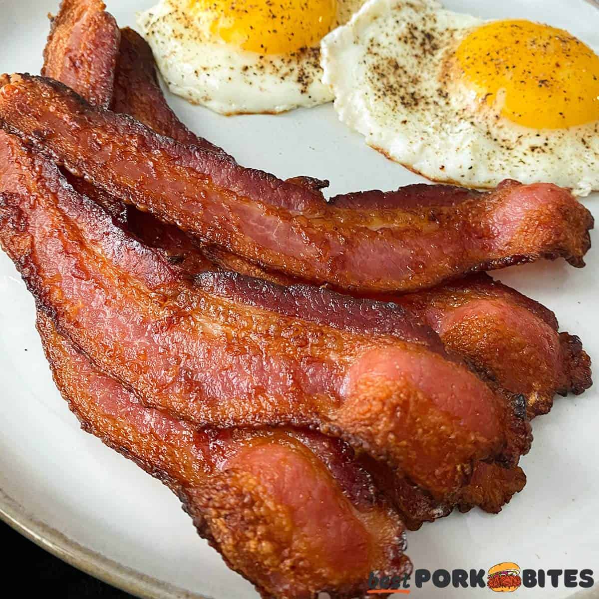 air fried bacon on a grey plate with eggs to the side