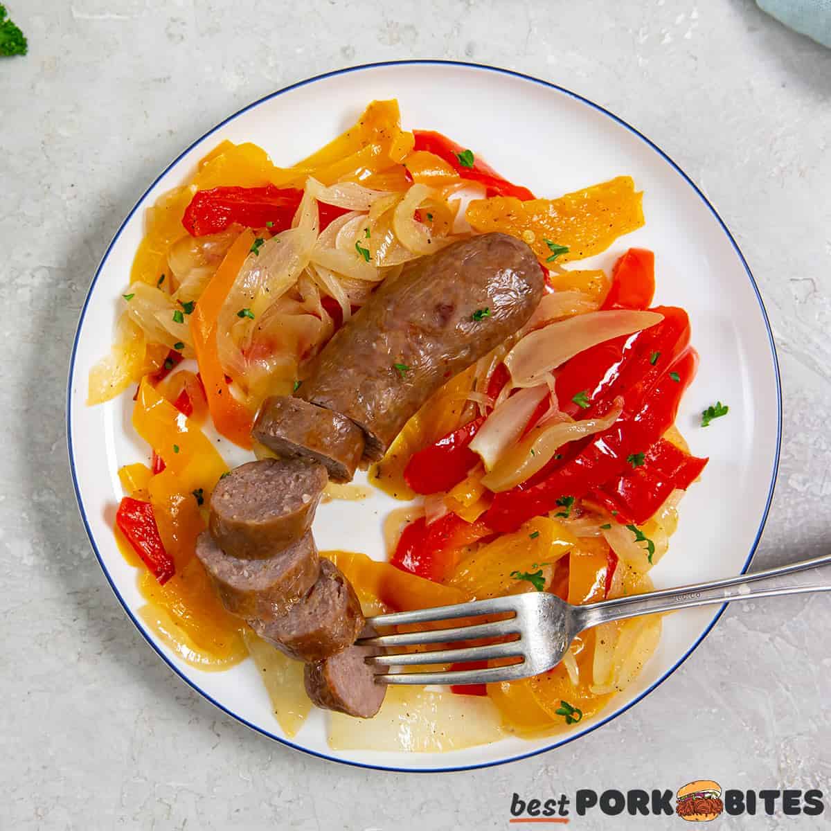 air fryer italian sausage sliced on a plate with onions and peppers