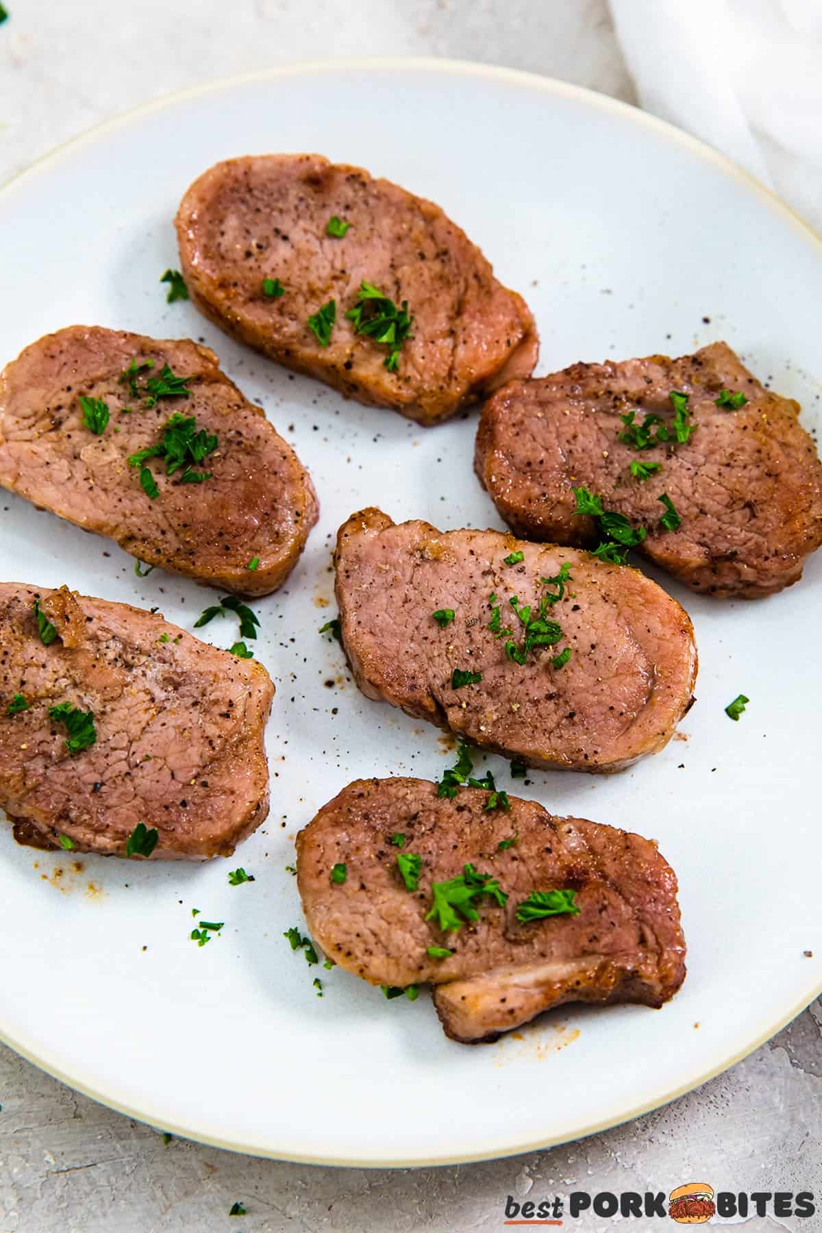 completed pork tenderloin on a white plate with parsley