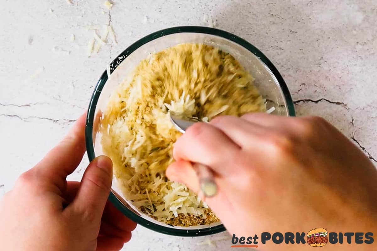 hands stirring pork chop seasoning in a glass dish with a fork