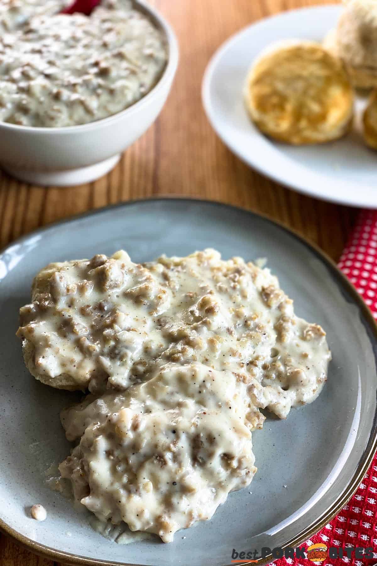 a plate of biscuits with sausage gravy next to a bowl of gravy and more biscuits