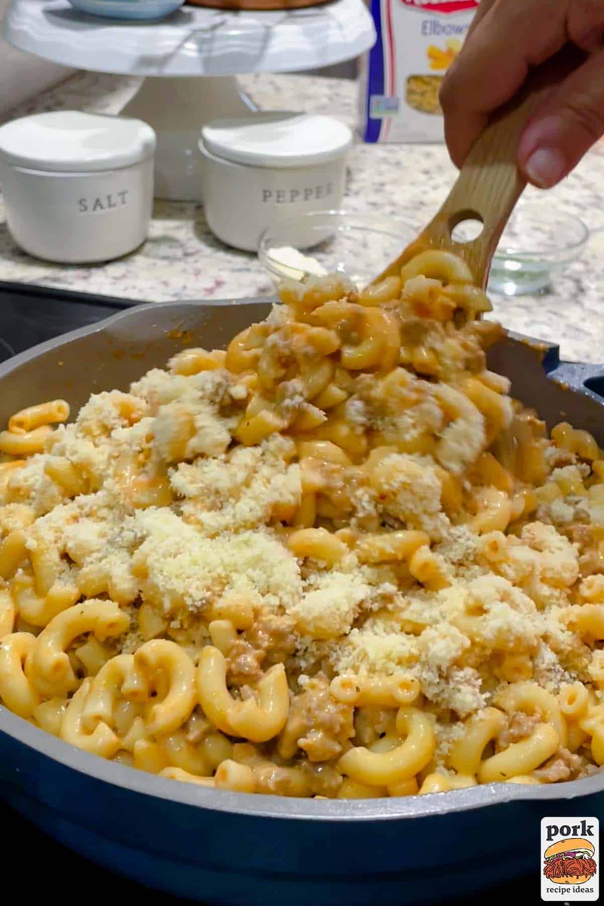 parmesan added to creamy sausage pasta in a pan