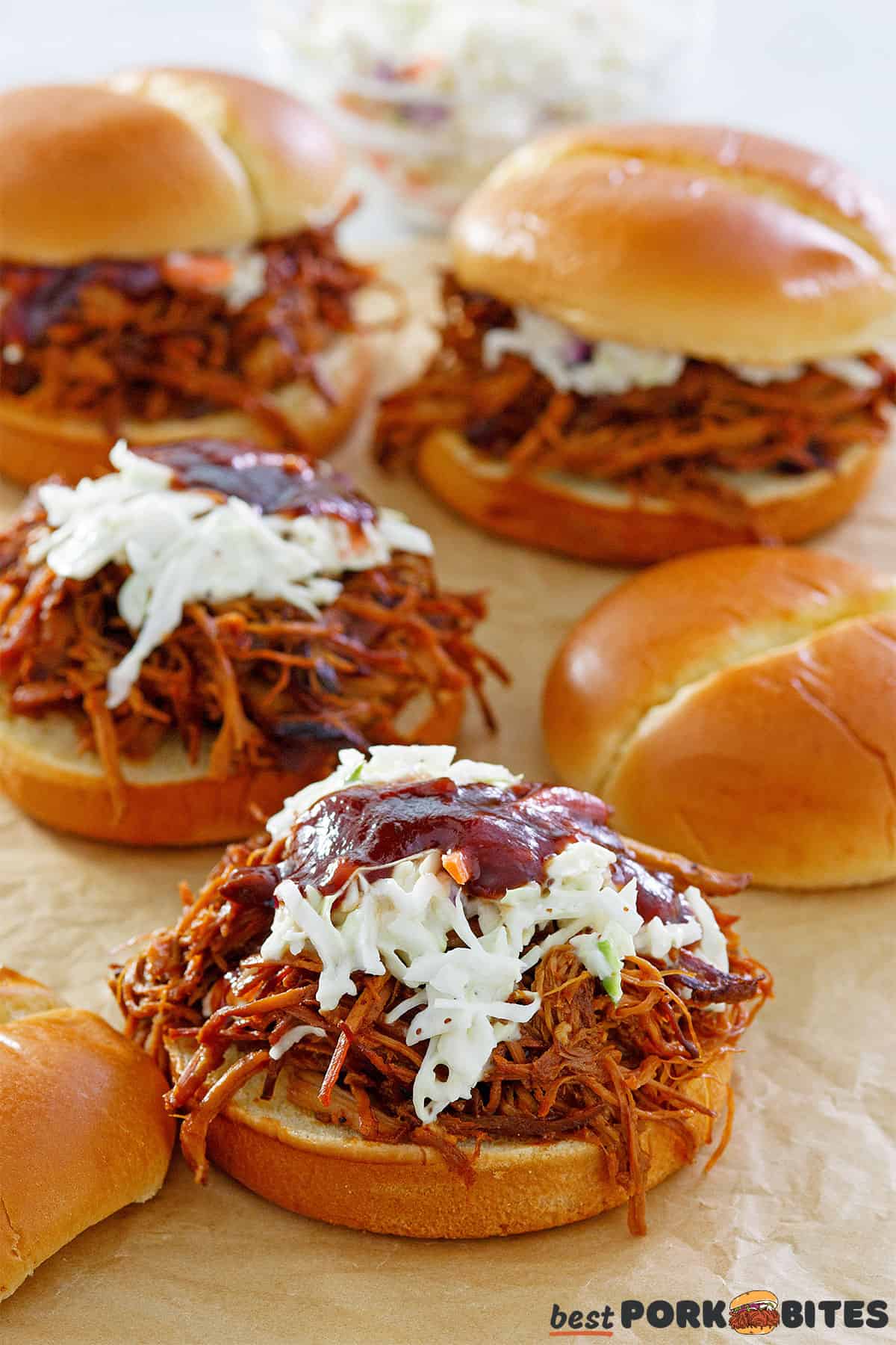 four crockpot pulled pork sandwiches with coleslaw and bbq sauce