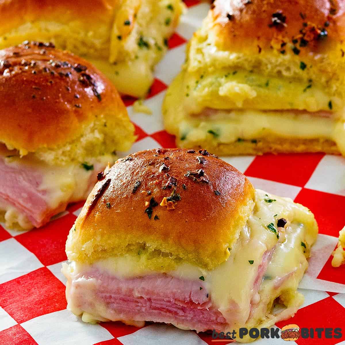 close up of baked ham and cheese sliders on butcher paper