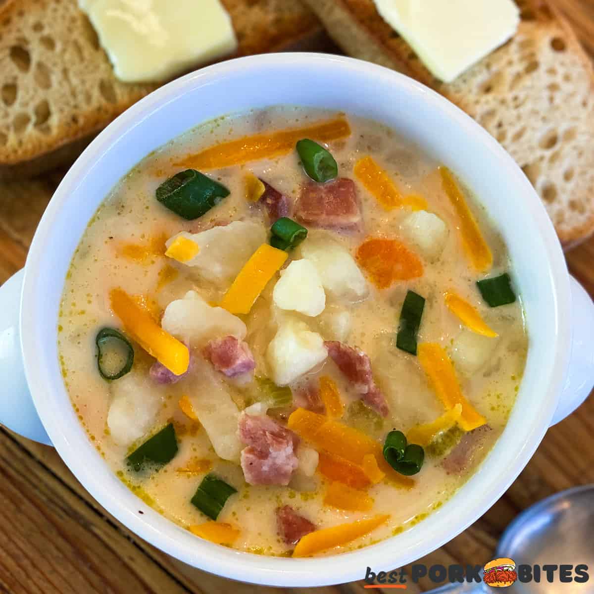 a bowl of ham and potato soup with cheese and bread
