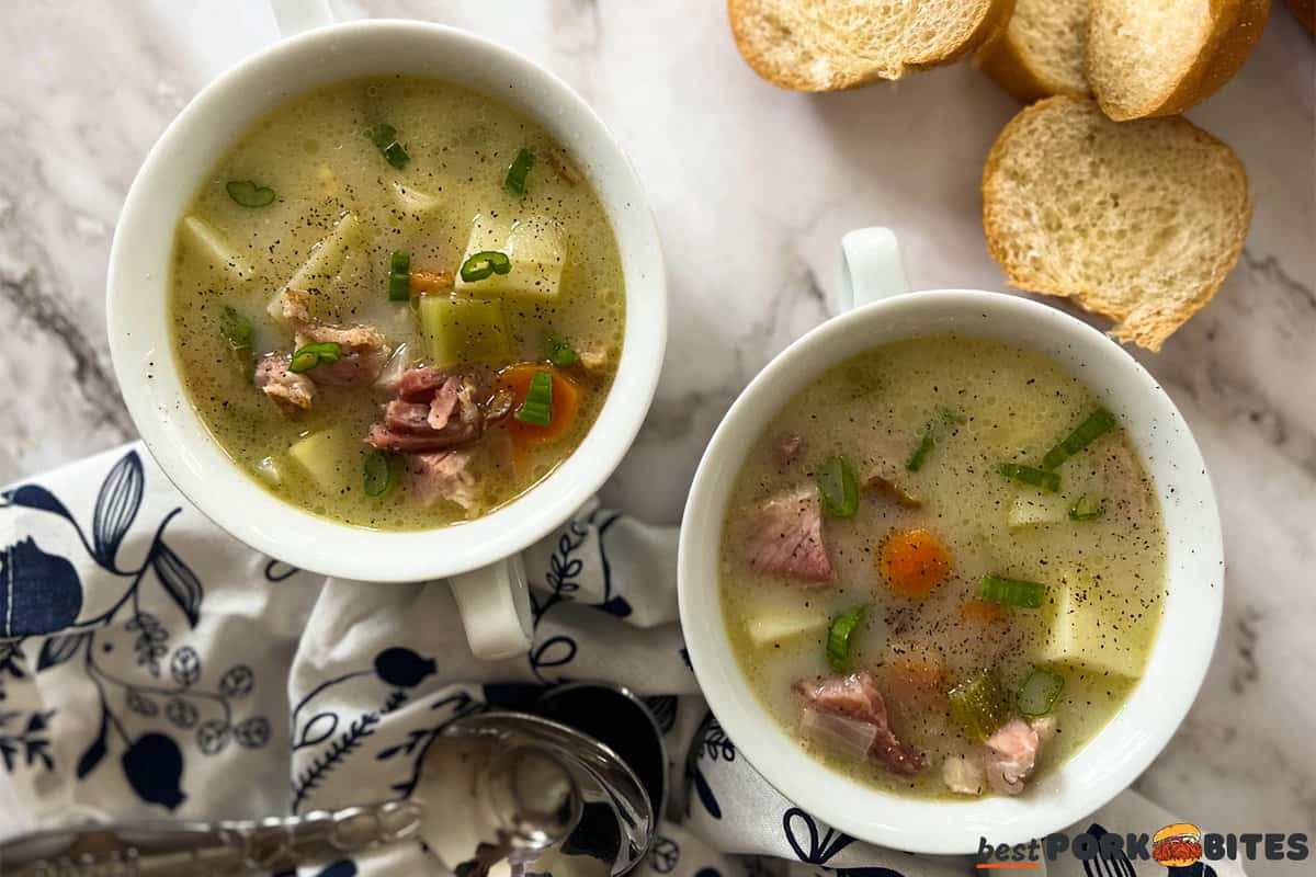 two completed bowls of ham bone soup with pepper and bread chunks.