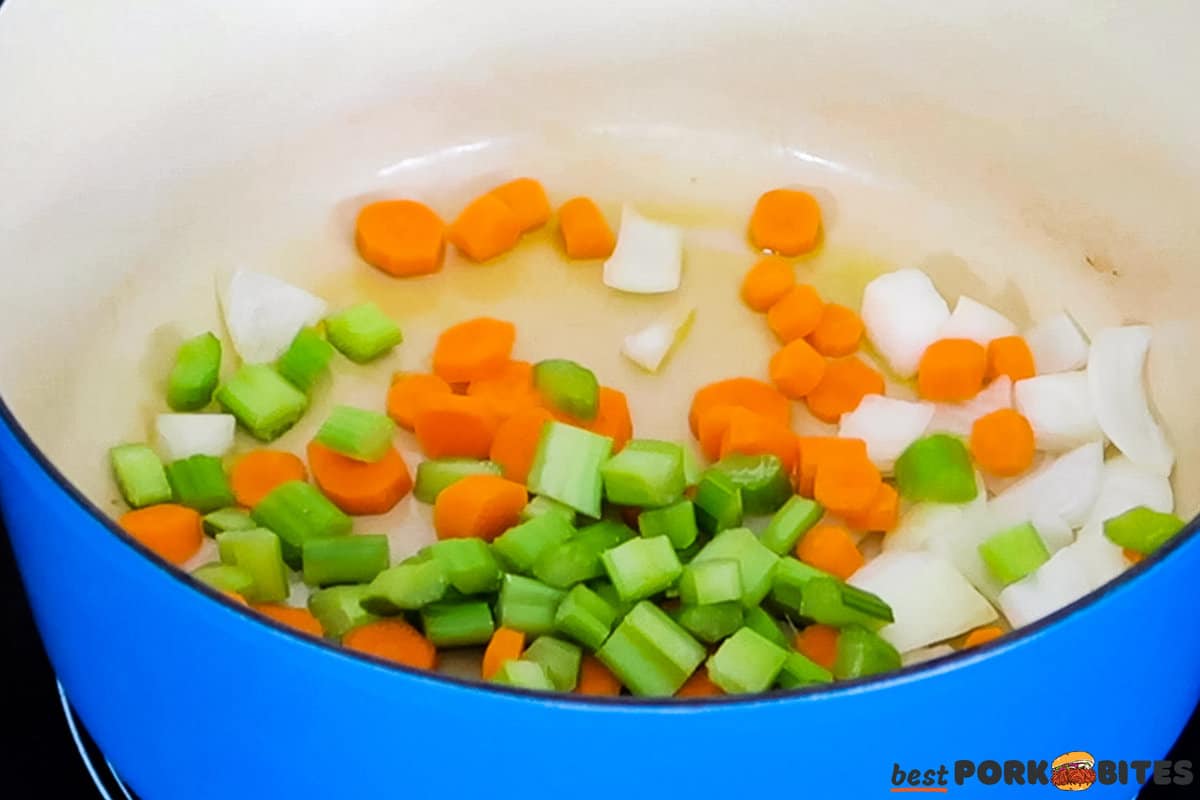 a pan with olive oil, carrots, onions, and celery added.