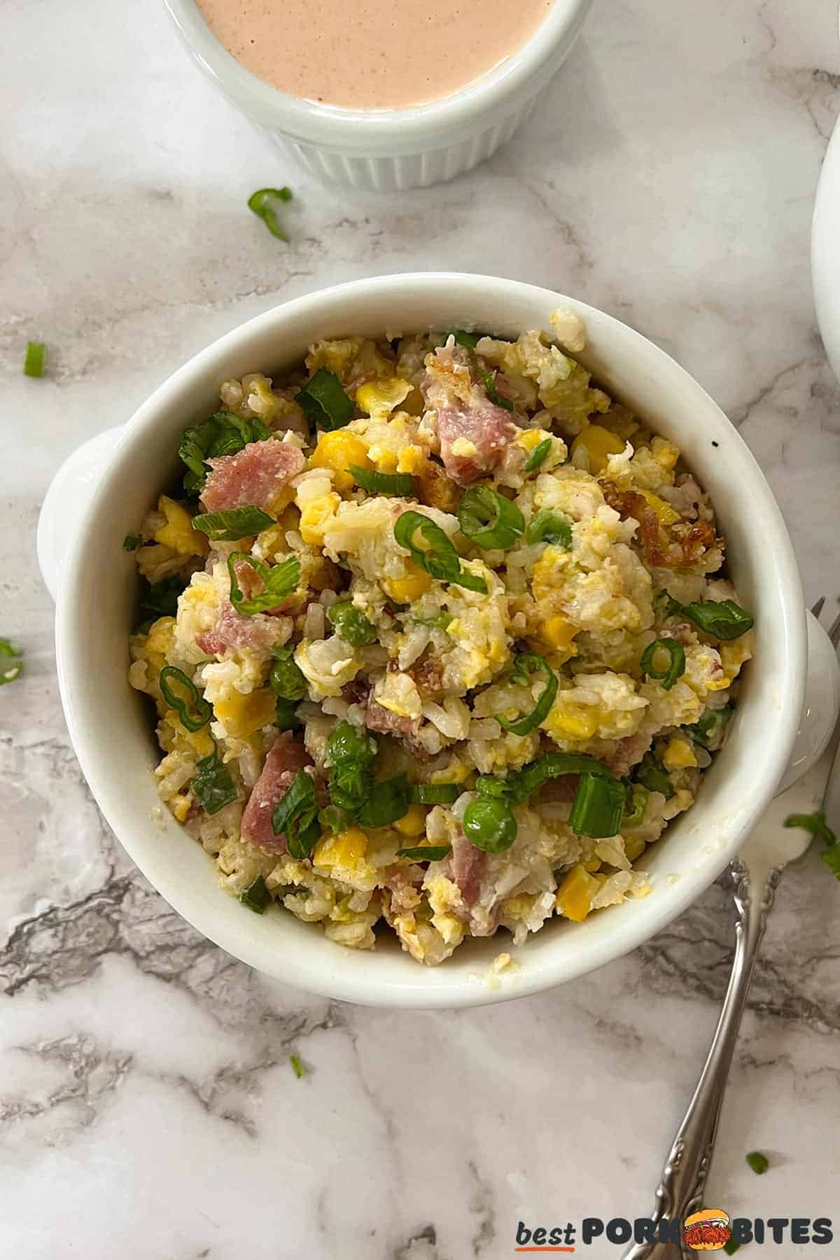 ham fried rice in a white bowl with a fork on the side